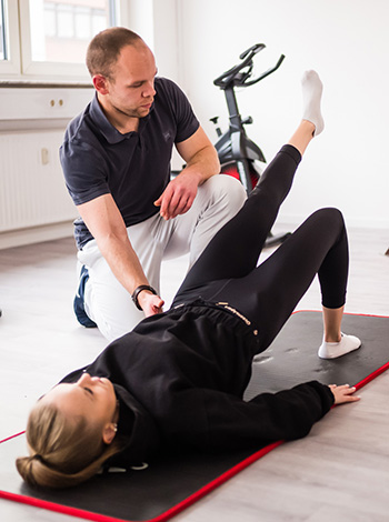 Krankengymnastik mit Physiotherapeut auf einer Matte