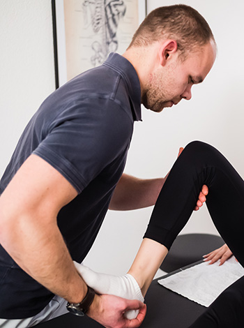 krankengymnastik physiotherapeut behandelt bein und fuß