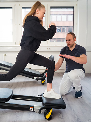 physiotherapeut mit patientin trainiert am geraet