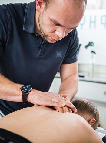 Physiotherapeut mit zwei Händen auf Frauenrücken