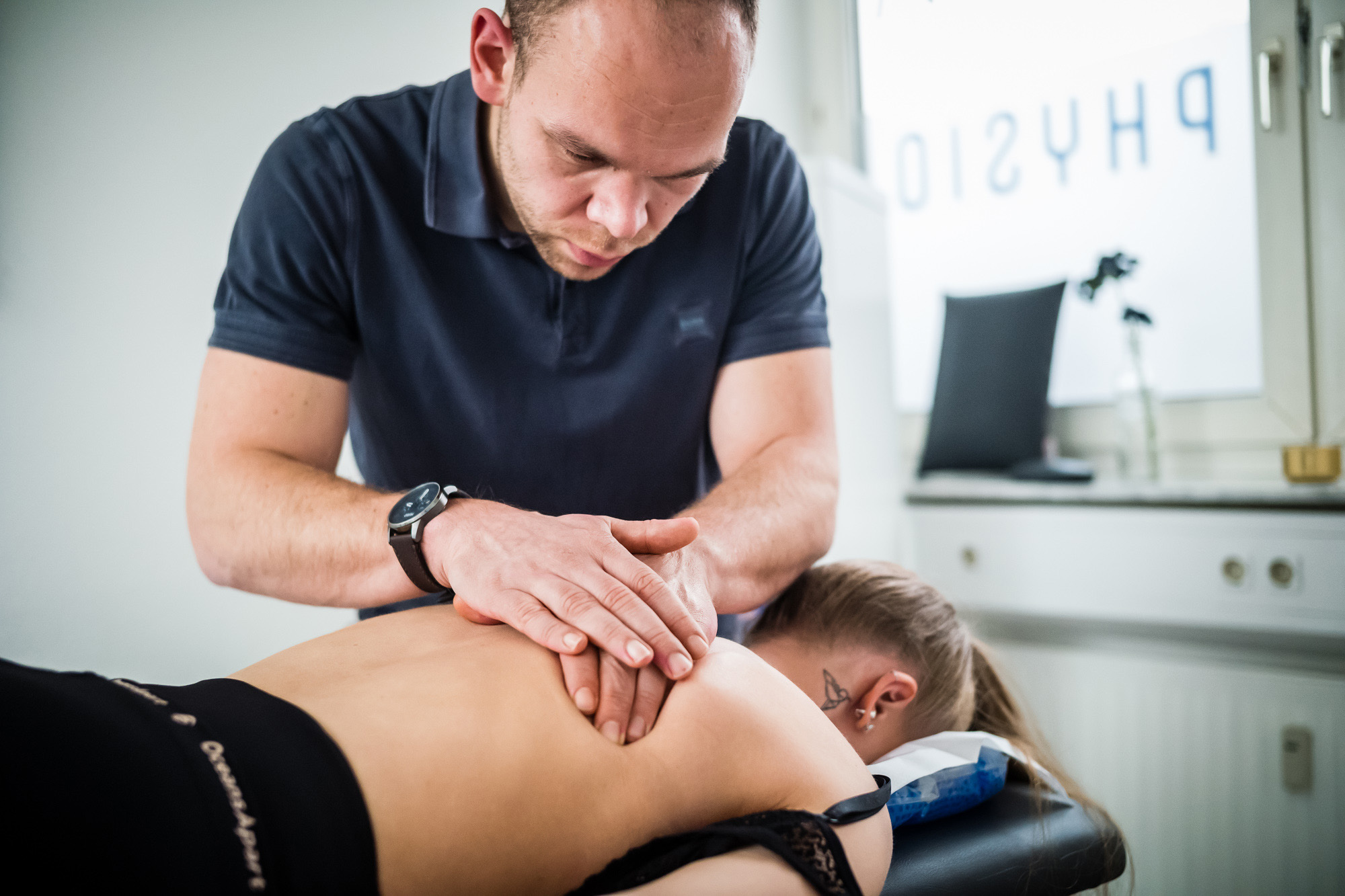 Physiotherapeut massiert mit zwei Händen den Rücken