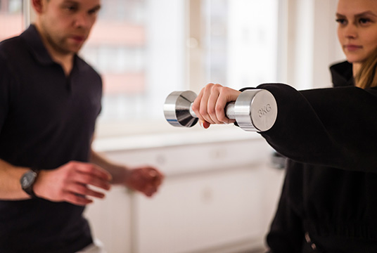 Physiotherapeut trainiert mit einer Patientin mit einer Hantel