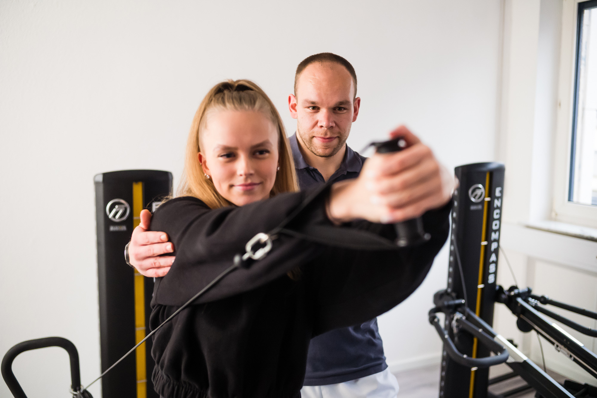 Physiotherapeut trainiert mit einer Patientin am Fitnessgerät